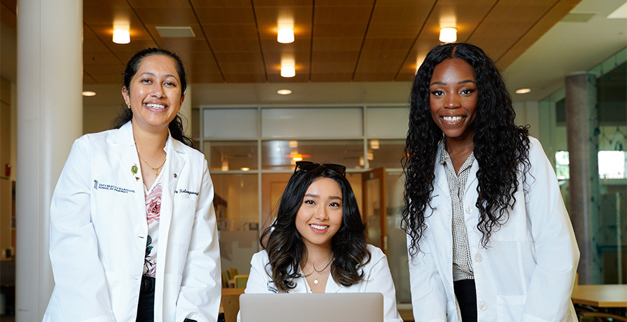 Three PharmD students wearing white coats